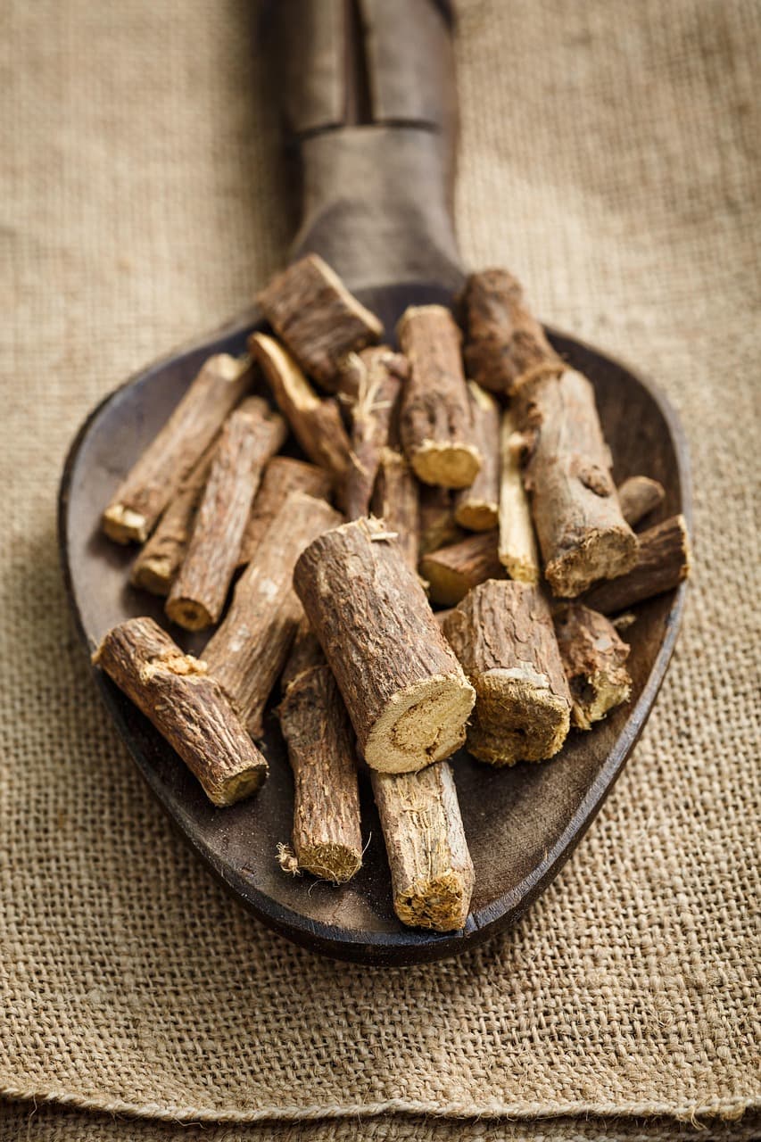 Dried licorice root sticks on a wooden scoop